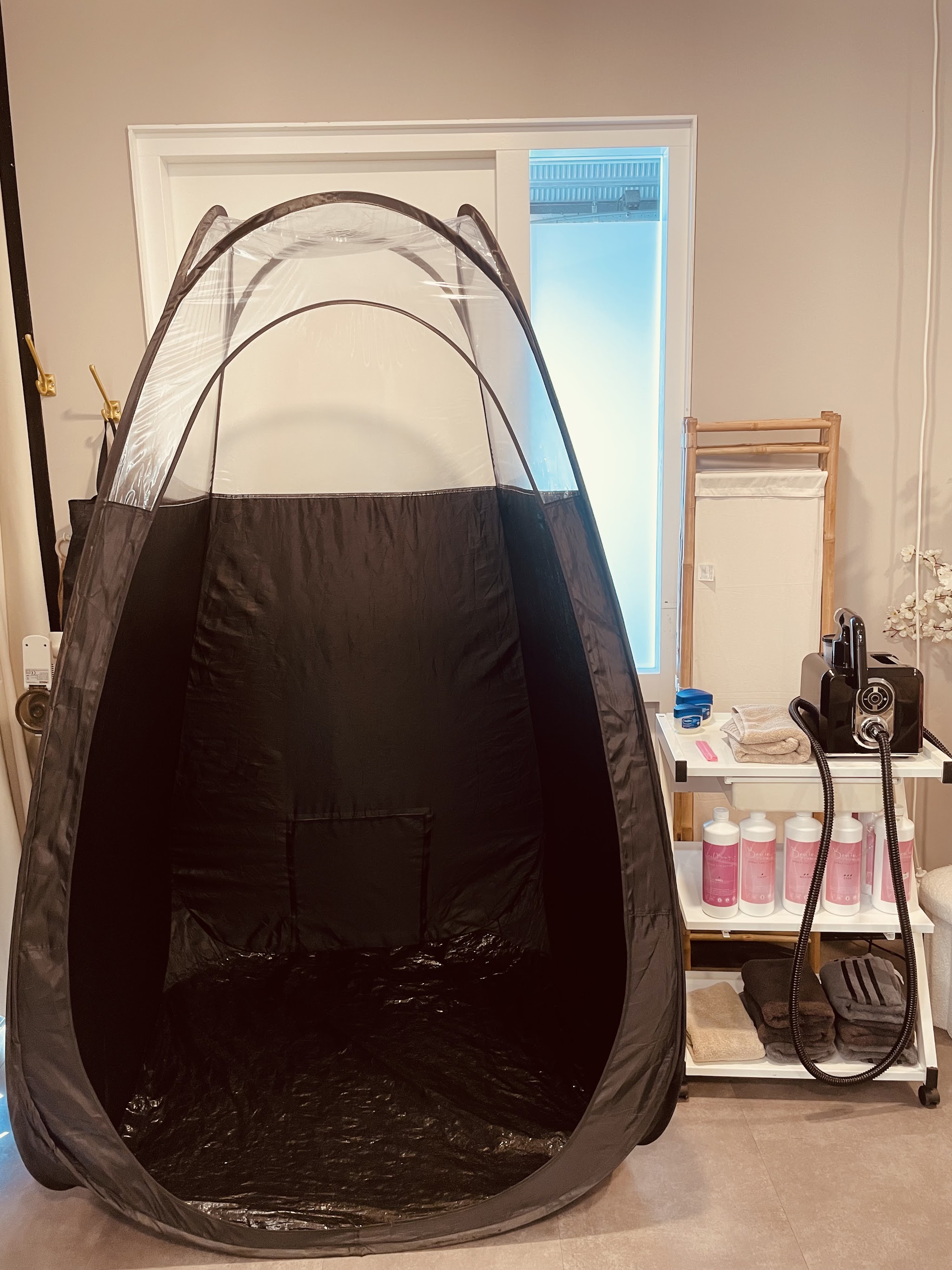 De pop-up spraytantent in de salon, met het tanapparaat ernaast